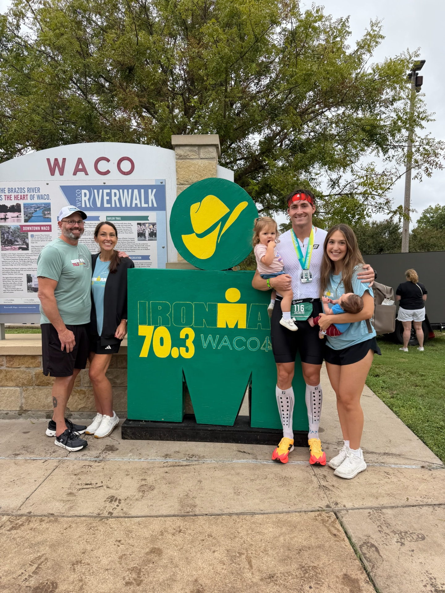 Zach Archer, race bib 116, finishing the IRONMAN 70.3 Waco race on October 6, 2024 with his family at the finish line